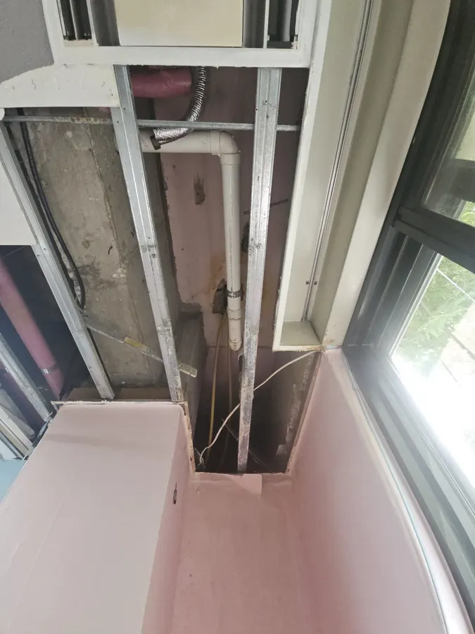 창가 에어컨 케이스 옆 천장 일부를 철거해 내부 배관이 보이는 모습